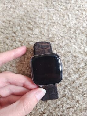 fitbit smartwatch with black screen and brown nylon band